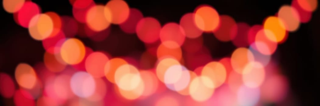 Bright, colorful lights illuminate the outdoor area, reflecting the joyful spirit of a festive evening celebration. People gather to enjoy the vibrant ambiance.