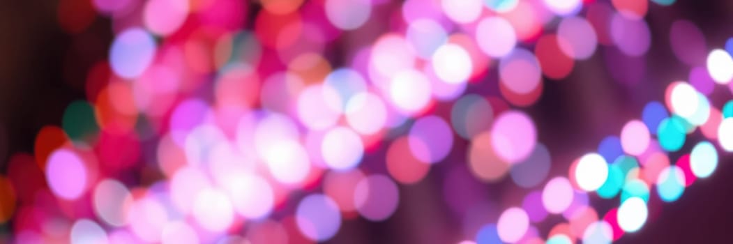 Bright, colorful lights illuminate the surroundings, creating a lively ambiance for a celebration. Attendees enjoy the enchanting display in the evening.