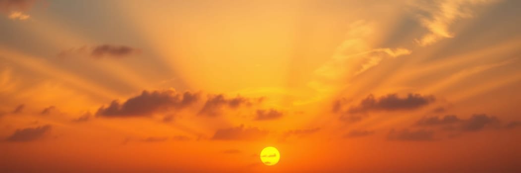 Golden sun setting on the horizon, casting warm orange and yellow hues across the sky, with soft clouds creating a tranquil atmosphere as daylight fades.