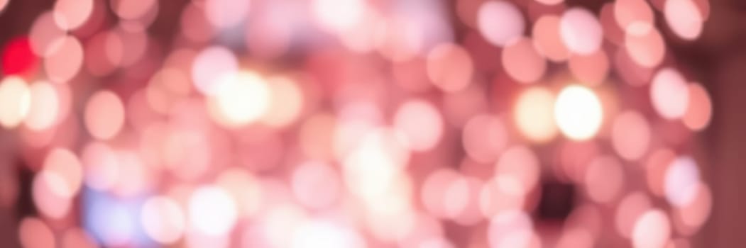 Soft, shimmering lights fill the area, creating a magical ambiance for the evening gathering. People move about, celebrating together amidst the beautiful display of warm colors.