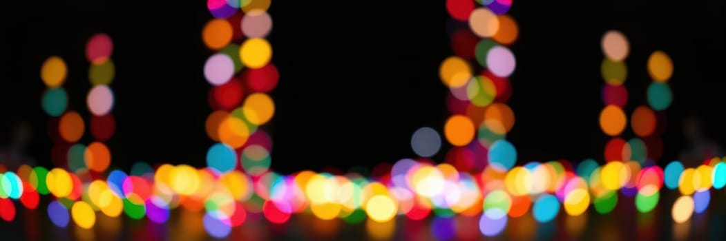 Bright, out-of-focus lights illuminate the surroundings, providing a vibrant and cheerful backdrop for a nighttime gathering in an urban environment.