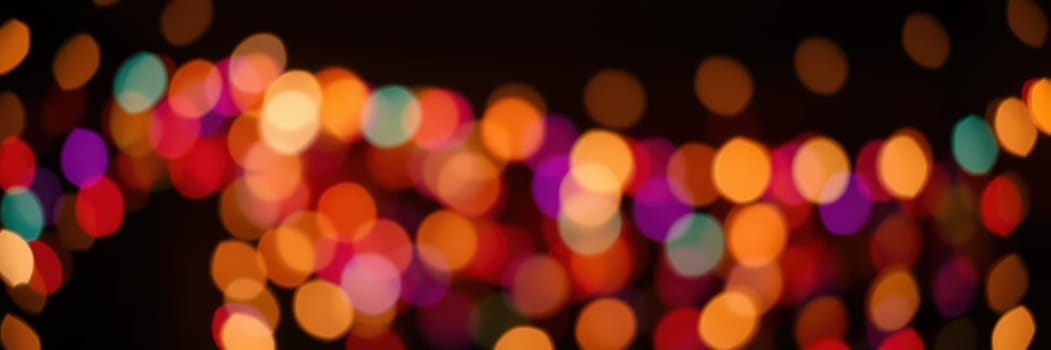 Vibrant, multicolored lights illuminate a dark setting, adding a cheerful and festive ambiance to an evening gathering. The bokeh effect enhances the visual charm.