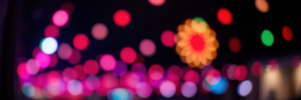 Brightly colored lights illuminate an urban area during an evening event, creating a lively and joyful ambiance filled with excitement and energy.
