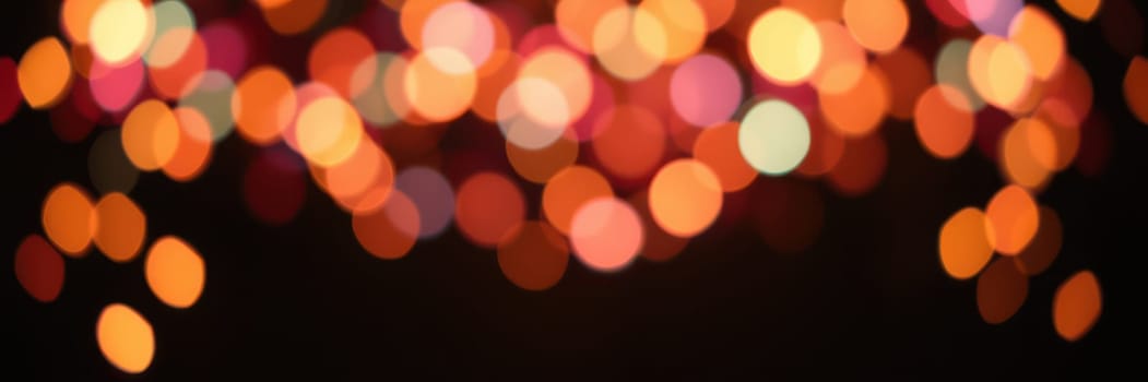 A dazzling display of blurred bokeh lights in vibrant colors decorates the evening sky, enhancing the joyful ambiance of a lively celebration or event.