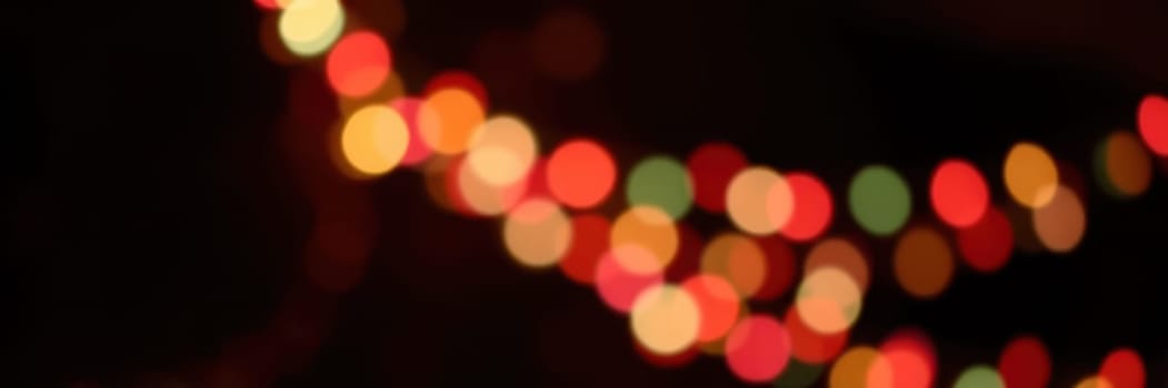 Bright string lights emit a warm glow in various colors, enhancing the festive ambiance of an evening gathering. The blurred background adds depth and charm to the scene.