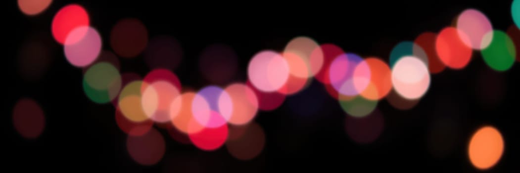Colorful bokeh lights illuminate the dark surroundings, creating a joyful and lively ambiance during a nighttime celebration in an urban setting.