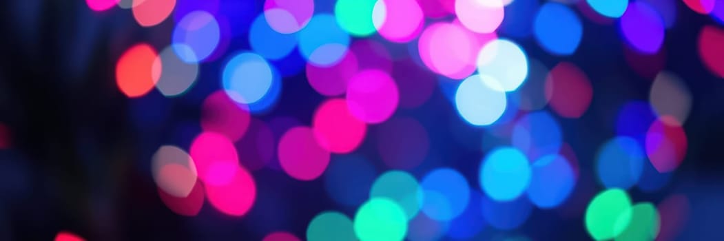 Soft, blurred lights in shades of pink, blue, green, and purple illuminate a lively atmosphere, enhancing an evening of celebration and joy. The colorful display captivates attendees.
