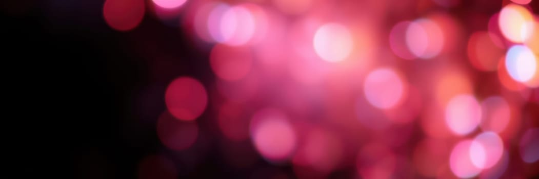 Colorful bokeh lights in shades of pink illuminate the night, enhancing the festive mood of a city celebration. The soft glow adds warmth and excitement to the surroundings.