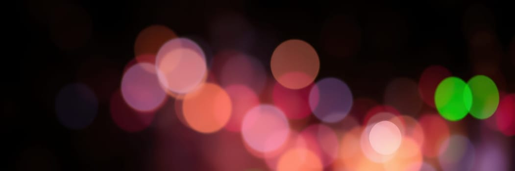Vibrant bokeh lights illuminate the background during a lively evening celebration, with various colors blending together to create an enchanting ambiance.