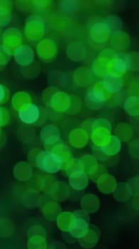 Vibrant green bokeh lights create a captivating background filled with shimmering spots, evoking a sense of tranquility and dynamic energy. This artistic effect enhances visual appeal.