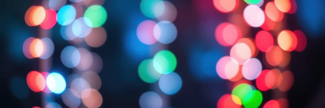 Softly blurred colorful lights twinkle in various shades, creating a lively and inviting atmosphere in an urban area during an evening celebration or event.