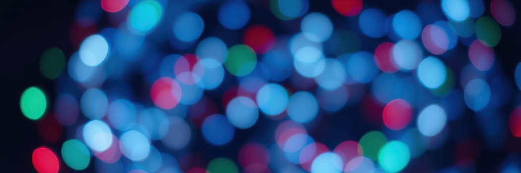 Blurred colorful lights in shades of blue, red, and green illuminate the night, creating a vibrant and cheerful atmosphere for a holiday celebration.