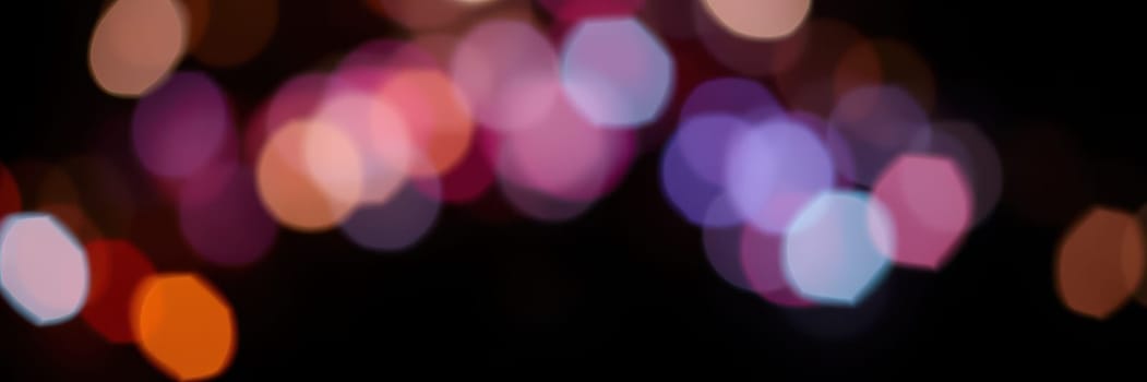 Bright, colorful bokeh lights illuminate the night, creating a lively ambiance for an outdoor celebration. The blurred lights in various hues enhance the festive mood.