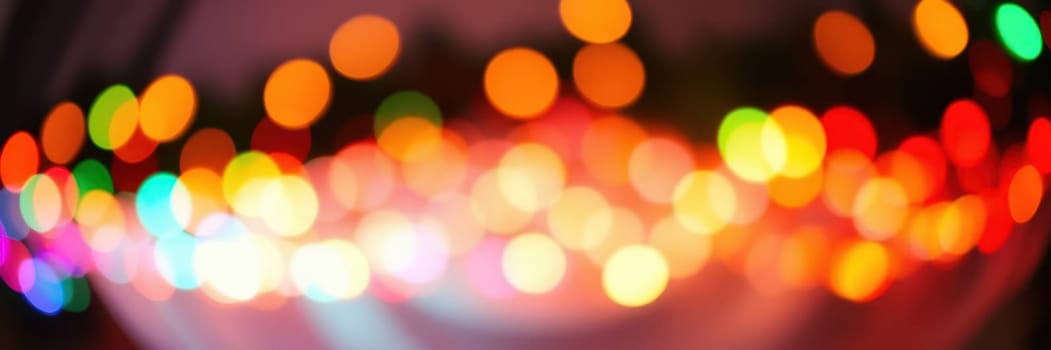 Brightly colored bokeh lights fill the background, creating a festive ambiance at a nighttime event. The warm hues suggest a cheerful gathering among friends and family.