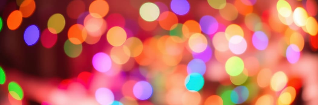 Softly blurred colorful lights twinkle in a warm ambiance, filling the space with a festive spirit during an evening gathering, enhancing the cozy atmosphere.