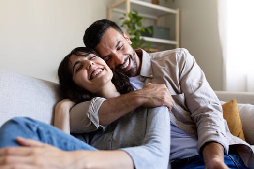 Affectionate happy couple in love hugging, relaxing on the couch. Love and relationships concept.