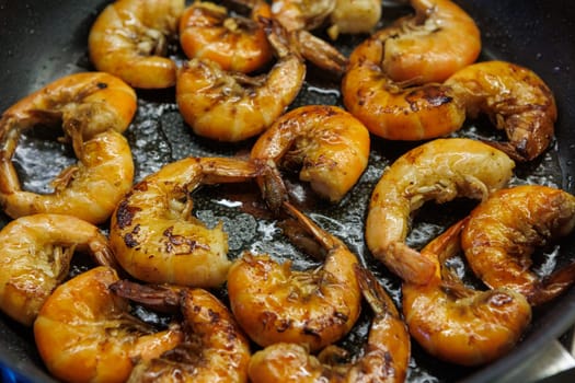 Golden pan-fried shrimp sizzling in a skillet, showcasing their rich, juicy texture and vibrant color. Ideal for use in cookbooks, restaurant menus, or gourmet advertisements