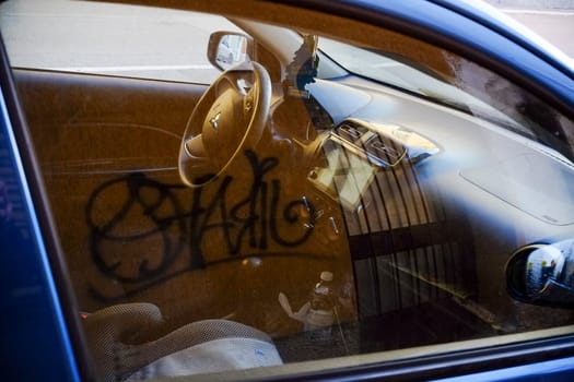 Cremona, Itally - October 6th 2024 Interior view of a vandalized mitsubishi space star showing graffiti on a dusty window
