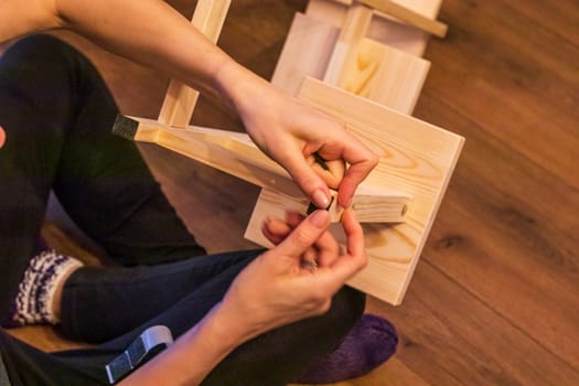 Woman is assembling wooden shelf