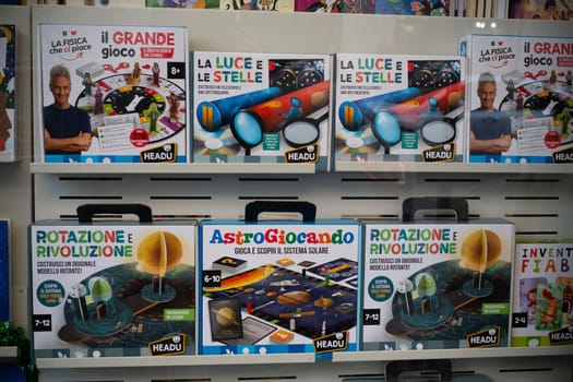 Cremona, Italy - November 27th 2024 Boxes of science-themed educational games for children. Focusing on astronomy. Physics. And light. Are neatly arranged on shelves in a store window