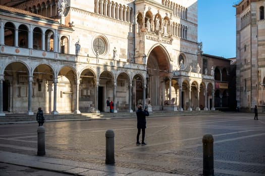 Cremona, Italy - November 27th 2024 Tourist taking pictures of the facade of cremona cathedral in piazza del comune, lombardy, italy