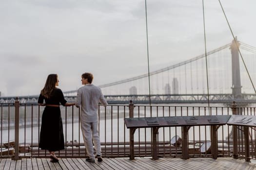 A beautifully romantic moment was captured between an affectionate couple, framed by a stunning bridge backdrop. Manhattan and Brooklyn bridge in New York.