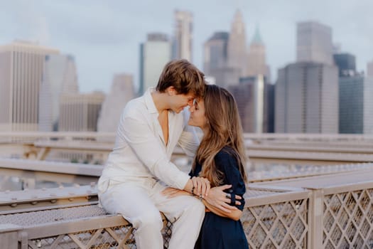 A lovely couple shares a sweet, tender kiss on the iconic Brooklyn Bridge, with the stunning NYC skyline behind them