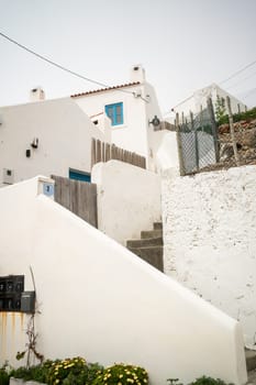From below of white houses and steps in small town of Portugal. Low angle shot of small buildings against clear sky during daytime.