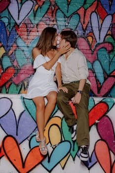 A couple kisses in front of a vibrant heart mural, symbolizing their love in a lively urban setting