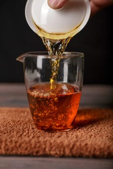 A beautiful closeup shot of a hand skillfully pouring a warm, aromatic liquid into a glass, highlighting the beverage