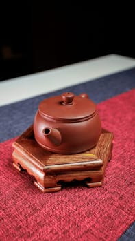 A beautifully crafted and artistic clay tea pot placed elegantly on a wooden stand, showcasing classical elegance