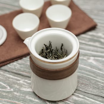 A beautifully designed, stylish tea infuser prominently showcasing loose leaf tea, with elegant cups in the background