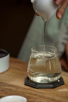 In a serene setting, hot water is poured into a beautifully crafted glass cup, perfect for tea lovers