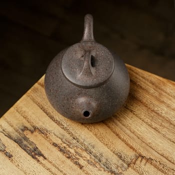 A stunningly beautiful, dark iron teapot gracefully placed on a rich textured wooden surface creating warmth