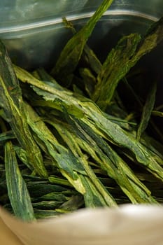 This is a closeup image focusing on dried green leafy herbs, highlighting their unique texture and form intricately
