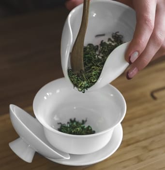 A skilled hand gracefully pours fresh, vibrant herbs into a chic white bowl in preparation for a delightful herbal tea