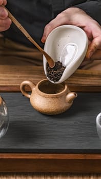 A lovely assortment of loose tea varieties is being elegantly poured into a beautifully handcrafted teapot for brewing