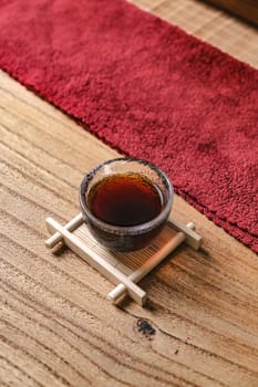 A beautifully stylish tea cup elegantly placed on a wooden tray, surrounded by rich, textured red fabric