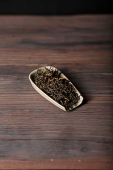 An exquisite artistic arrangement of loose leaf tea presented elegantly in a ceramic dish placed on rustic wood