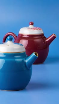 Stylish blue and brown teapots are beautifully and thoughtfully displayed on a vibrant and lively purple backdrop