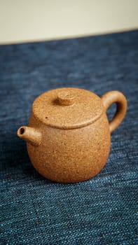 An artisancrafted clay teapot beautifully showcasing its unique design on a stylishly textured fabric backdrop