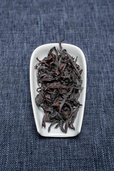 A close-up of dried black tea leaves in a decorative dish, showcasing their unique texture and color.