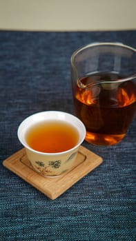 An elegant tea presentation with a traditional cup and modern glass, beautifully arranged on a textured surface