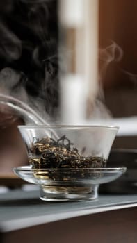 A calm and serene scene of steaming loose leaf tea expertly brewing in a beautiful glass bowl, inviting warmth