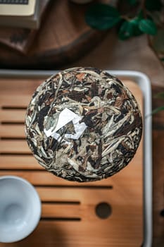 A beautifully arranged artisan jar filled with loose leaf tea on a rustic wooden tray, perfect for tea lovers