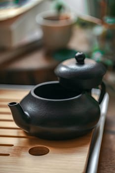 A beautifully crafted black teapot, elegantly poised on a wooden tray, ideal for passionate tea enthusiasts everywhere