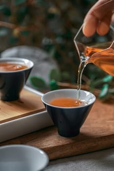 A tranquil scene depicting tea being carefully poured into elegant cups, all surrounded by lush greenery