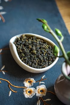 An attractive arrangement of fresh green tea leaves in a decorative bowl, set against a vibrant floral background