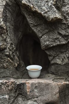 A serene and calming scene featuring a delicate tea cup gently resting on a rocky surface, symbolizing true tranquility
