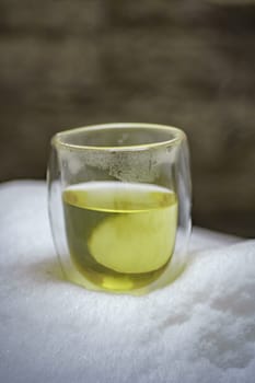 A stunning glass filled with a green beverage set against a snowy backdrop, showcasing nature's contrast.